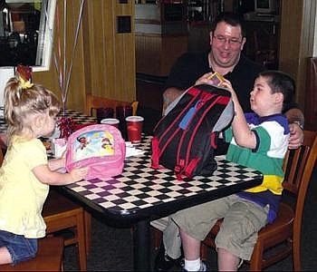 Grayson Smith shows his dad, Ray, one of the items from a backpack of goodies from the Dream Factory. At left, Grayson's sister Mara looks at the backpack she received. 