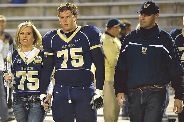 Helias lineman Gavin Frevert is accompanied by his parents, Roger and Charlotte, as he takes the field during Senior Night on Thursday at Adkins Stadium.