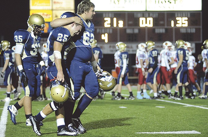 Crusader junior Garrett Brooks (62) comforts senior Greg Lorang (25) after Helias lost its Class 4 Sectional game 35-21 to the Webb City Cardinals on Monday night at Adkins Stadium. 