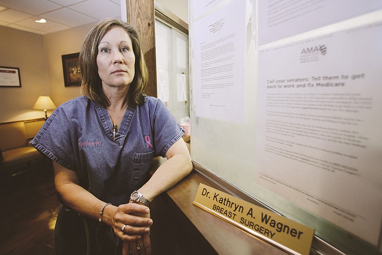 AP.Dr. Kathryn Wagner, a breast cancer surgeon, poses next to notices related to Medicare at her office on Wednesday in San Antonio. Wagner and other doctors are rebelling over a 25 percent cut in Medicare fees that goes into effect Dec. 1 - unless the lame duck Congress staves it off.