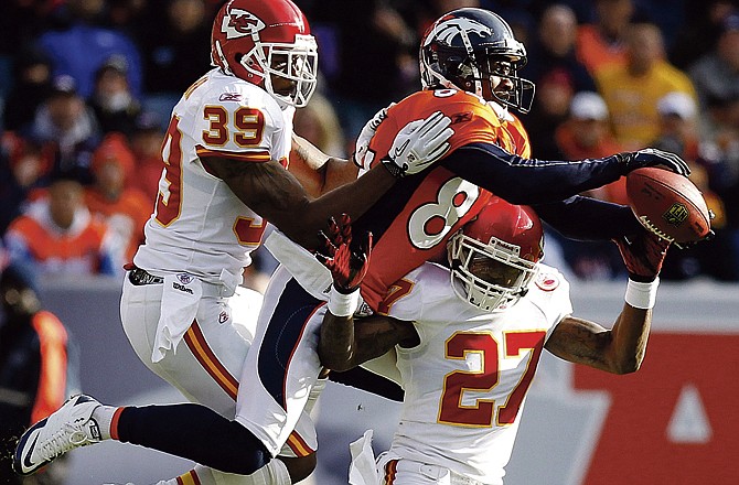 Denver Broncos wide receiver Brandon Lloyd (84) goes over the top of Kansas City Chiefs cornerback Donald Washington (27) to catch a pass for a first down in the first quarter of an NFL  football game on Sunday, Nov. 14, 2010, in Denver.  Also defending on the play for the Chiefs is Brandon Carr (39).