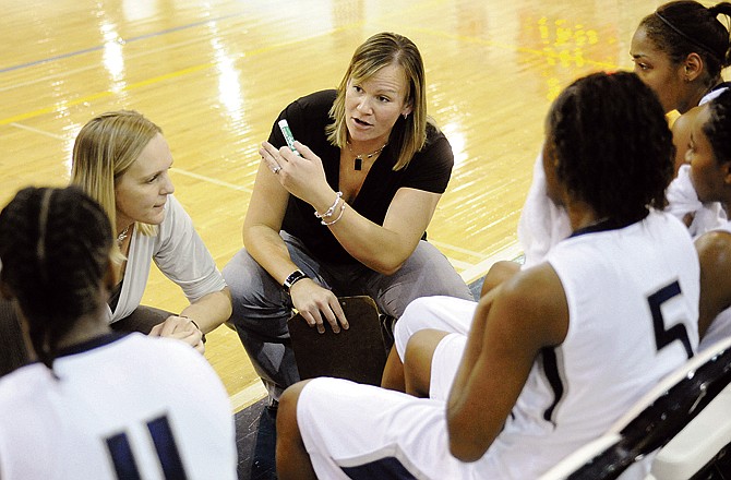 Lincoln assistant women's basketball coach Nicole Collier, center, explains strategy during a timeout late in regulation time during the Blue Tigers' game against Rockhurst on Friday evening at Jason Gymnasium. Head coach Katie Vaughn is at center left. 