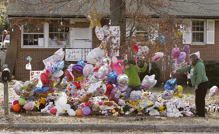 AP.Allison Kolb, right, and Casey Tillman, left, place items at memorial for Zahra Baker in front of the last home of Adam and Elisa Baker in Hickory, N.C., on Thursday.