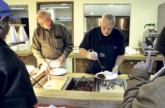 Don Calvert and Steve Whitlock serve up meals Thursday at the free community meal at Jefferson City's First Baptist Church in the Fellowship Hall. The church will also cook a free Thanksgiving meal on Thanksgiving Day. 