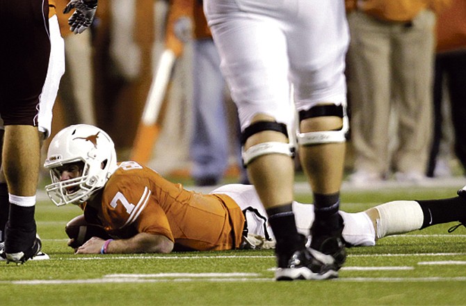 Texas' Garret Gilbert (7) lays on the turf after he was sacked by Texas A&M during the second quarter of their college football game, Thursday, Nov. 25, 2010, in Austin, Texas.