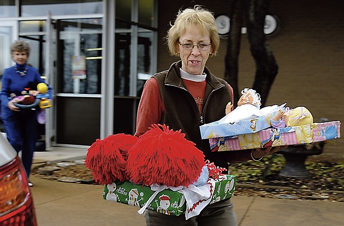 Karen Phelan from Community Christian Church carries dolls to a car for delivery. Over the summer, volunteers purchased the dolls, then made or bought clothing and blankets for them. The dolls are being donated to the Salvation Army Center of Hope for resident children first and then distributed as needed. 