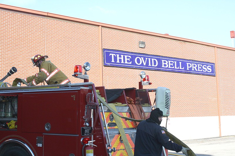 Mandi Steele/FULTON SUN photo: Firefighters work to return hoses to a fire truck after using them to extinguish a fire at The Ovid Bell Press.