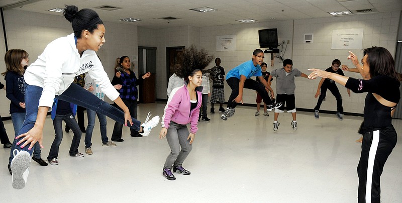 Seventh grade students Ajani Milton, left, and Faith Lewis, middle, participate in African dance as Thomas Jefferson Middle School celebrated the 14th Annual Tour of Africa Friday. Lincoln University's Dance TroupÅ½ students, under direction of Theressa Ferguson, at right, performed and worked with students in the dance demonstration.  Upon completion of weeks of study of the continent, its people and culture, food and history, students were treated to different aspects of the culture. Guest speakers helped to round out the day's celebration with slideshows, music, dance and clothing items native to different regions.