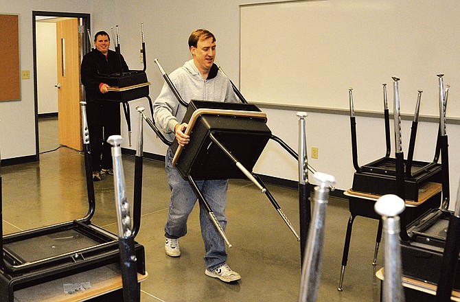 Principal Eric Ahlers and Dan Dearhoff carry in desks at the New Calvary Lutheran High School on Saturday. The school hopes to begin classes in their permanent home on Dec. 13. 