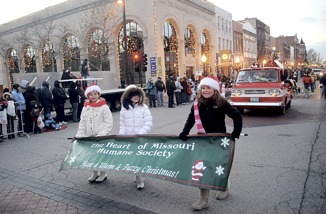 Bundled-up ambassadors for the Heart of Missouri Humane Society carry a banner of good wishes during Jefferson City's annual Christmas parade Saturday afternoon on High Street. 