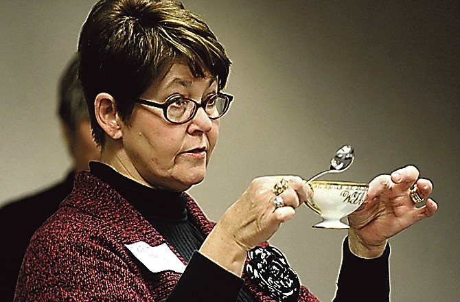 Betsy Thomas holds up a small soup dish, out of which it is proper to drink, during a demonstration on table manners to Jefferson City Area Young Professionals. Thomas is a docent with the Missouri Governor's Mansion and regularly gives lessons to youngsters, but this is a first time to adults. 