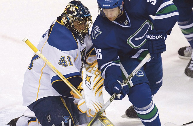 Vancouver Canucks' Jannik Hansen, right, gets the puck past St. Louis Blues goaltender Jaroslav Halak during first period hockey action at the Rogers Arena in Vancouver, Sunday, Dec. 5, 2010.