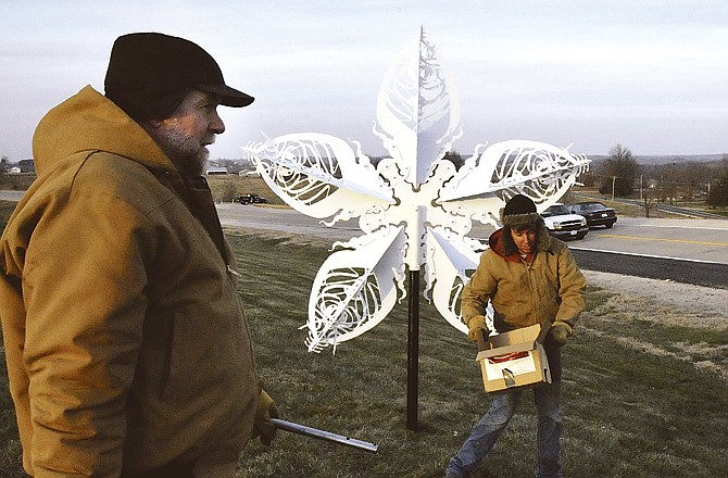 Charles, left, and Ian Steck clean up after installing the first large snowflake in Wardsville for "Art Inside the Park." 