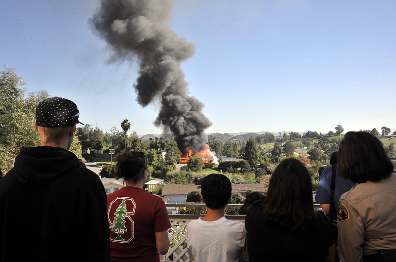 Neighbors look on as a house erupts in flames on Thursday during the controlled burn of a home in Escondido, Calif., that was so packed with homemade explosives that authorities claim they had no choice but to burn it to the ground. 