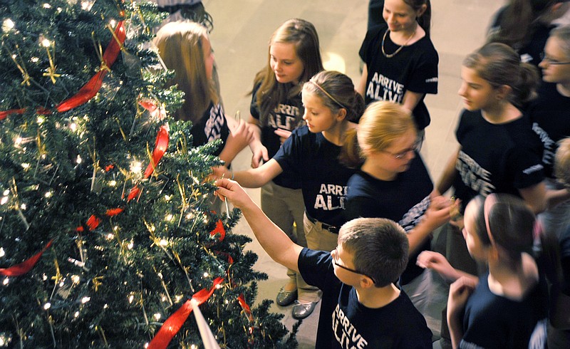 Fifth- and sixth-grade students from St. Stanislaus School select ornaments from a tree honoring victims of impaired driving Thursday in the Capitol Rotunda. Their choir performed Christmas carols at the beginning of the Missouri Remembers 2010 ceremony. 