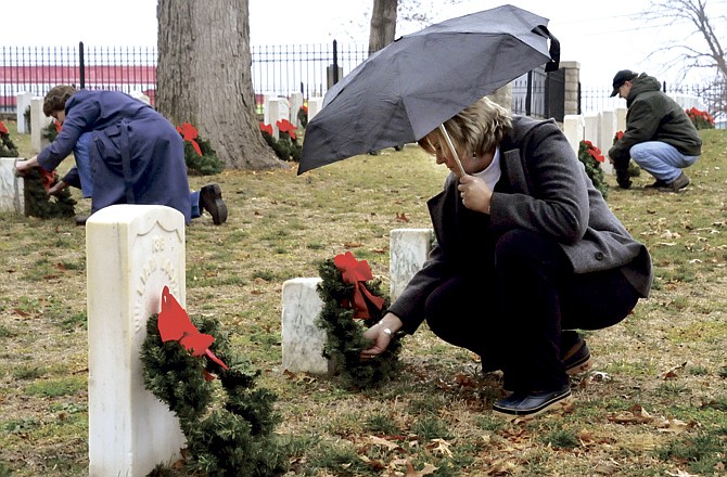 Jill Lawrence, foreground, was just one of many who assisted laying wreaths Saturday morning at the National Cemetery. The Wreaths for Heroes ceremony honoring the fallen servicemen was held at 10 a.m. The program has been held annually, but this is the first year where each marker was decorated with its own wreath. 