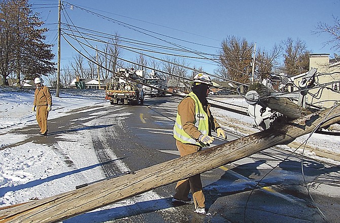 AmerenUE workers Lennie Voss, right, and Kurt Gentges start work Sunday afternoon to repair a utility line pole that snapped, bringing down the power lines over Green Berry Road. The road was closed to traffic. 