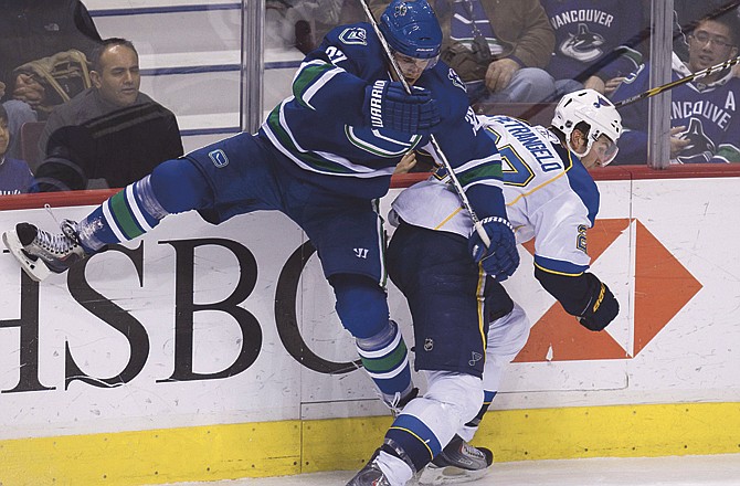 The Blues' Alex Pietrangelo (right), shown getting checked by the Canucks' Joel Perrault in a game Dec. 5 at Vancouver, will miss tonight's game against the Red Wings. 