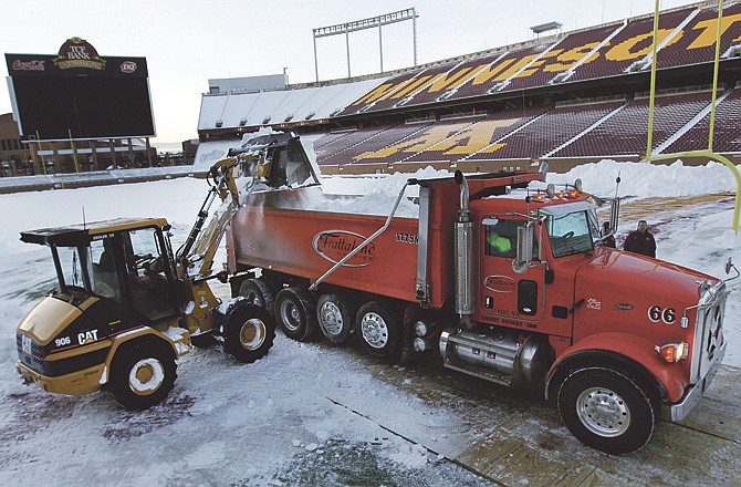 A front-end loader dumps snow into a truck as workers clean the field of TCF Stadium on Tuesday in Minneapolis. The Minnesota Vikings and Chicago Bears will use the stadium, the home field of the University of Minnesota, for their game Monday night. 