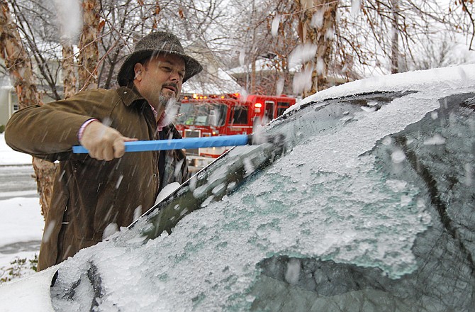 Bill Rouse scrapes thick ice off his windshield Thursday after freezing rain in Lexington, Ky. 