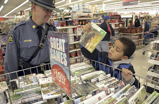 Tre Anthony and Lt. Steve Frisbie of the Missouri Highway Patrol pick out video games at Jefferson City's Kmart for Operation T.O.Y.S. (Take Our Youth Shopping) Saturday morning. The annual event allows needy children to pick out presents for themselves and their families. Officers from area law-enforcement branches assisted them with purchases. 