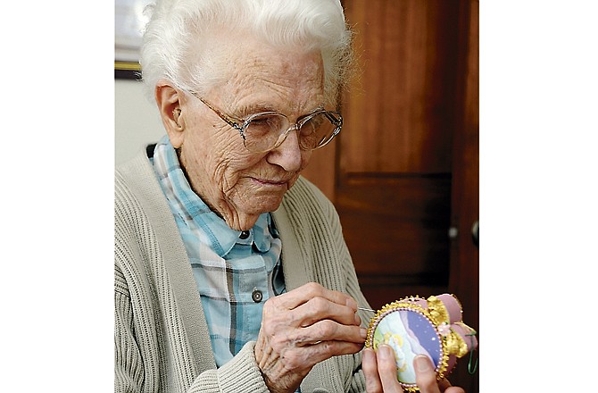 Pauline Markway demonstrates how she makes beaded ornaments from old Christmas cards at her home in Wardsville. Markway has created ornaments out of old greeting cards and family photos like the World War II photo of her husband for about 30 years. This year, she's made about 70 to give to friends and relatives. 