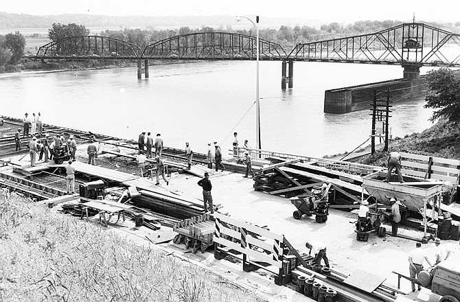 A file photo shows workers as they lay decking on the approach of Jefferson City's current southbound Missouri River bridge, opened in 1955, with the old 1896 Bolivar Street bridge in the background. The current northbound bridge was opened in 1991.