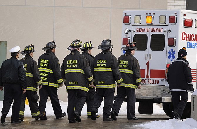 Chicago firefighters follow the ambulance carrying Chicago firefighter Edward Stringer's body at the Chicago Medical Examiner's office Wednesday. A blaze at an abandoned building on Chicago's South Side left two firefighters dead and 17 injured Wednesday. The fire happened on the 100th anniversary of the Union Stock Yards fire in Chicago, which killed 21 firefighters.