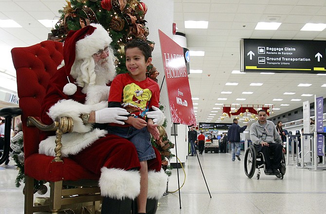 Mark Anthony Sepulveda, 6, of Hialeah, Fla., tells Santa his wishes for Christmas on Thursday at Miami International Airport. Holiday travelers were experiencing fairly easy trips, but wintry weather may make things more difficult this weekend.