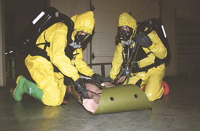 Staff Sgt. Robyn Boatright, left, and Sgt. 1st Class Juan Gallego, both of the Missouri National Guard's 7th Weapons of Mass Destruction Civil Support Team, secure a training mannequin to a SKED extraction device during an exercise at the Cole County Emergency Management Center. 
