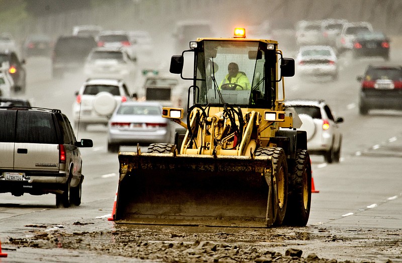 A Caltrans dozer operator scrapes mud Wednesday off the right three lanes of the eastbound 91 Freeway near Green River Road near Corona, Calif. A mudslide blocked parts of the freeway for up to six hours, authorities said.