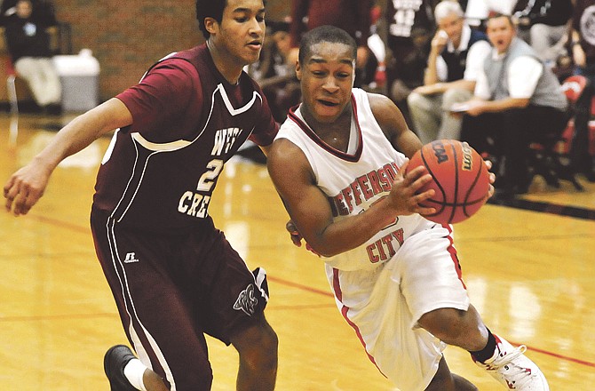 Brenden Jackson of Jefferson City drives around Ryan Carswell of West Creek on Tuesday night at Fleming Fieldhouse. 