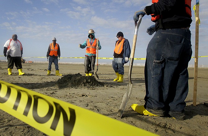 Workers prepare to fill a whole that was dug to search for a layer of tar buried under the sand on an East Grant Terre Island, La., beach. Beaches that once looked like excavation sites are returning to normal, but there is still oil underneath the sand, mud and oyster shells.