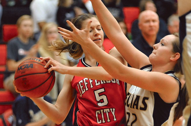 Sadie Theroff of the Jefferson City Lady Jays is closely defended by Arielle Chambers of the Helias Lady Crusaders in Thursday afternoon's third-place game in the State Farm Holiday Hoops Invitational at Fleming Fieldhouse.