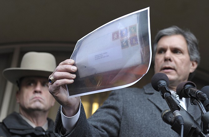 Maryland State Police spokesman Greg Shipley, right, holds up a copy of a photo of a letter that was mailed to Maryland Gov. Martin O'Malley, in Annapolis, Md., on Thursday during a news conference outside the Jeffrey Building. At left is A.J. McAndrew with Maryland State Police field operations. 