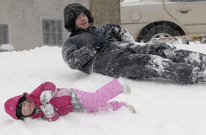 Joe Arnold and his daughter Leah Arnold roll down the sled hill Tuesday at McNaughton Park in Elkhart, Ind. The county has received several inches of system snow with more lake effect snow on the way.