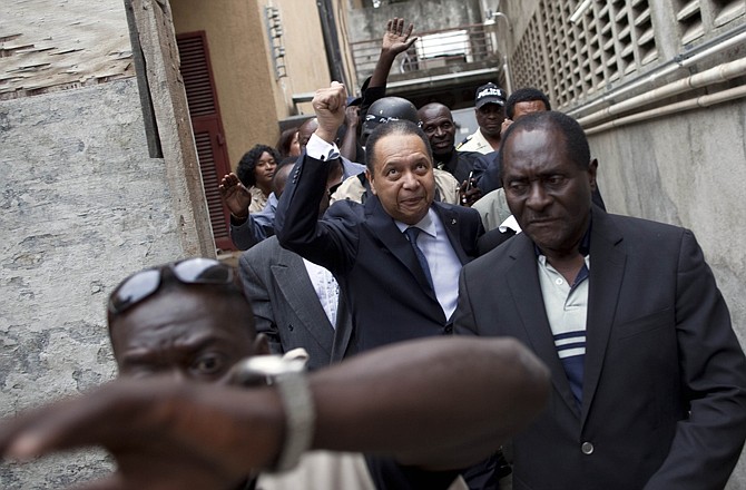 Haiti's ex-dictator Jean-Claude Duvalier, center, gestures to supporters Tuesday as police take him out of his hotel in Port-au-Prince, Haiti. A legal case was opened against Duvalier nearly 25 years after he was ousted from power.