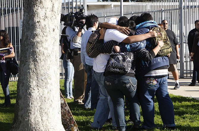 Gardena High School students hug in a circle Tuesday as they leave the school grounds in Gardena, Calif., after two students were wounded when a gun in a student's backpack went off.