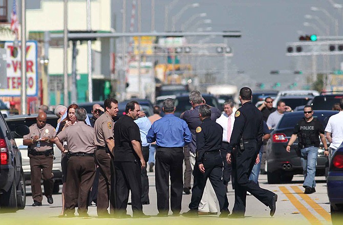 Police officers gather near the location of a shootout Thursday that erupted in a Miami neighborhood, killing two Miami-Dade police officers and a suspect. 