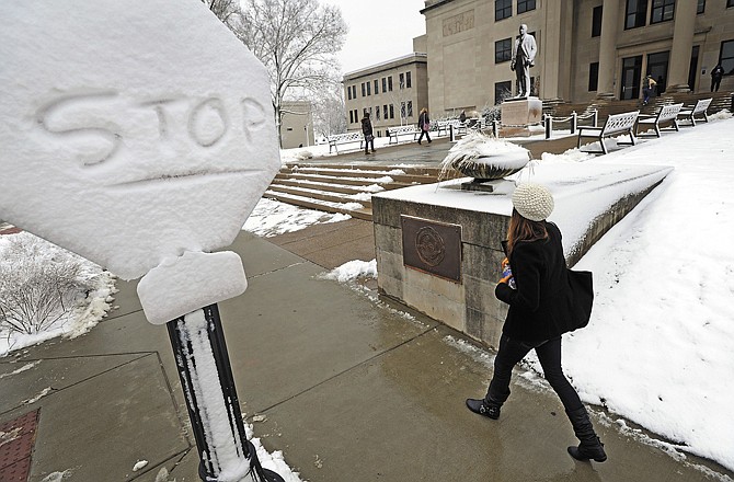 A Western Kentucky University student walks past a snow-covered stop sign on campus Wednesday in Bowling Green, Ky. Several inches of snow blanketed south-central Kentucky.