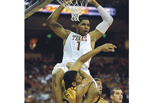 Texas forward Gary Johnson, top, holds onto the rim while wrapped around Missouri center Steve Moore, bottom, after attempting a dunk during the first half in an NCAA college basketball game Saturday, Jan. 29, 2011, in Austin, Texas. 