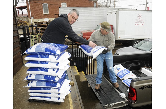 Dave Vogel, left, hands to Alan Bennett bags of ice melter as they fill yet another early morning customer's order. Both work at Pay Way Feed Store on Jefferson Street and were very busy Monday morning helping customers load their purchases.