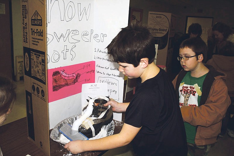 Mandi Steele/FULTON SUN photo: Auxvasse Elementary School student Ben Bondurant shows how his invention, snow sweeper boots, works on Tuesday night at the Invention Convention held at Auxvasse Elementary.