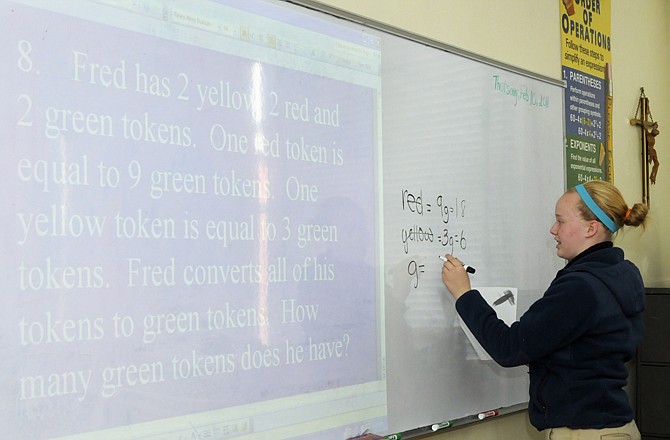 Seventh-grader Maggie Stiefferman works out the answer to a math question on the board in front of the rest of the class as they practice for today's MathCounts competition at St. Peter School.