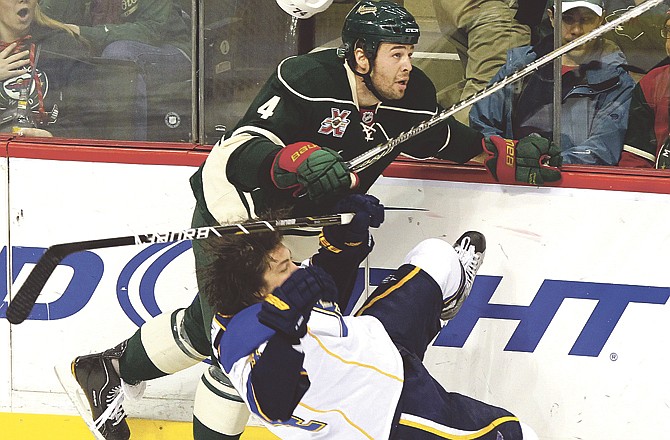 St. Louis Blues' T.J. Oshie loses his helmet and falls to the ice as he checks Minnesota Wild's Clayton Stoner during the first period of an NHL hockey game Saturday, Feb. 12, 2011, in St. Paul, Minn. 