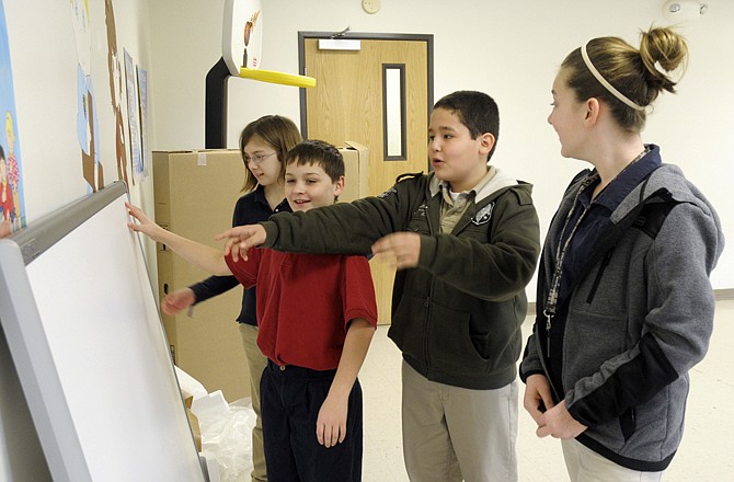Adrienne Skelton, near, Anthony Figueroa, both fifth-graders, and Brenden Janeczko and Hannah Hughes, both fourth-graders, look at and touch the SmartBoard received last week at Concord Christian School. They were amazed at the smooth texture of the new equipment. The board was donated and delivered by Hy-Vee and presented to an appreciative and excited school.  