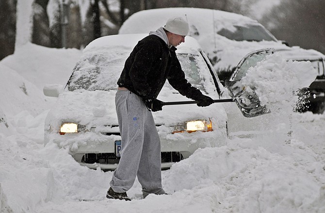 Grant Seipkes digs out a car Monday in Minneapolis. Nearly a foot of snow clogged the streets and sidewalks as people began the task of digging out. 