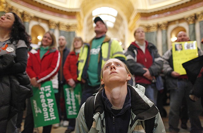 Lovesta Banks, center, and other protesters watch television monitors of Assembly hearings going on Tuesday inside the state Capitol in Madison, Wis. Opponents to Gov. Scott Walker's bill to eliminate collective bargaining rights for many state workers are taking part in their eighth day of protesting.