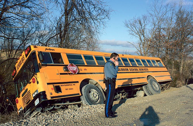 A New Bloomfield School District bus sits in a ditch off of Couny Road 432 after it slid off the road Monday. Trooper Andrew Armstrong of the Missouri State Highway Patrol investigates the accident.