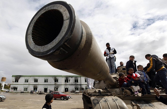 Libyan youth climb on a destroyed tank Thursday at Al-Katiba military base in Benghazi, Libya. The base fell to anti-Libyan Leader Moammar Gadhafi protesters few days ago. Army units and militiamen loyal to Moammar Gadhafi struck back Thursday against rebellious Libyans who have risen up in cities close to the capital.